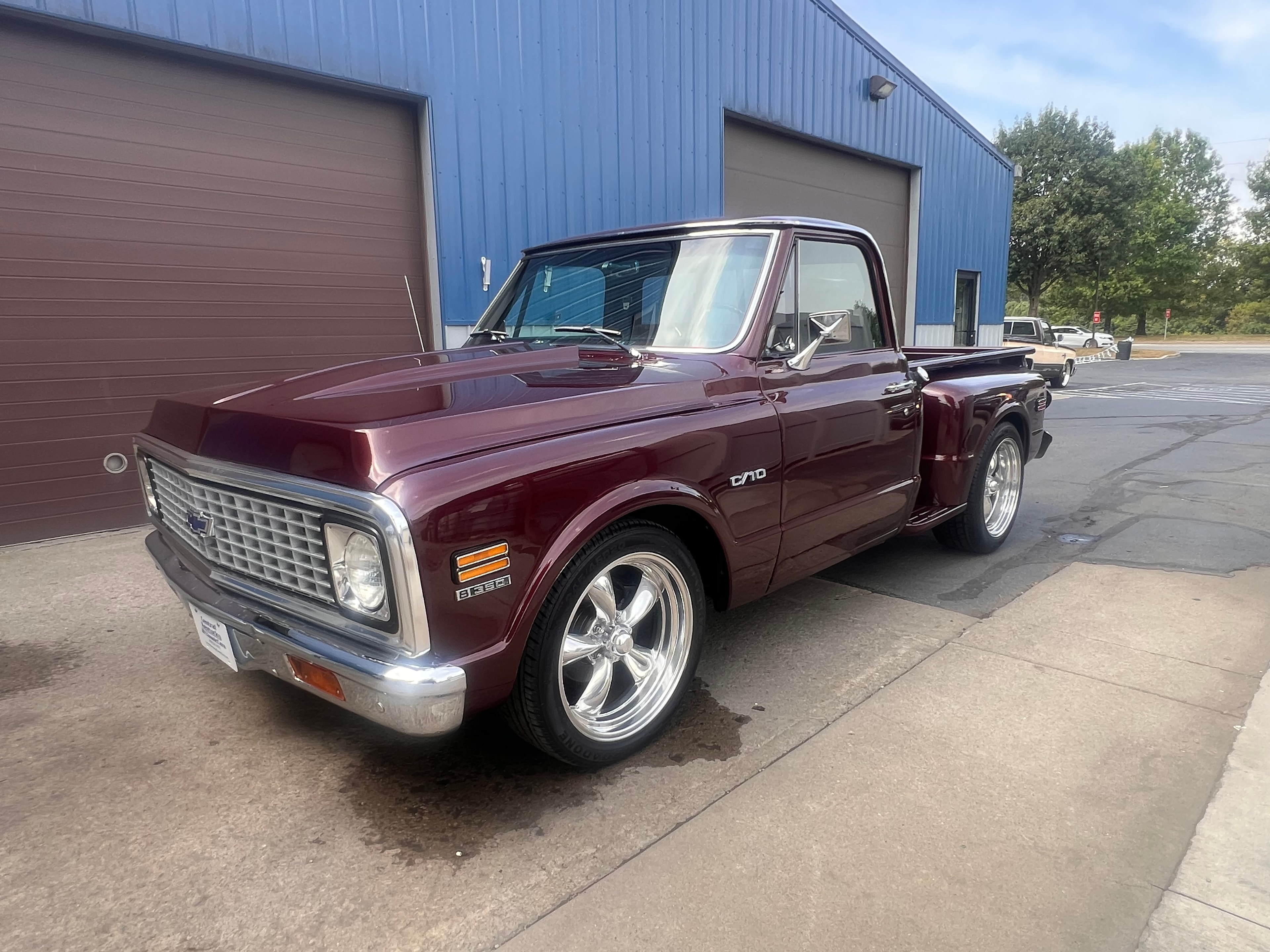 Burgundy 1972 Chevrolet C10 short bed with chrome Torq-Thrust wheels outside shop