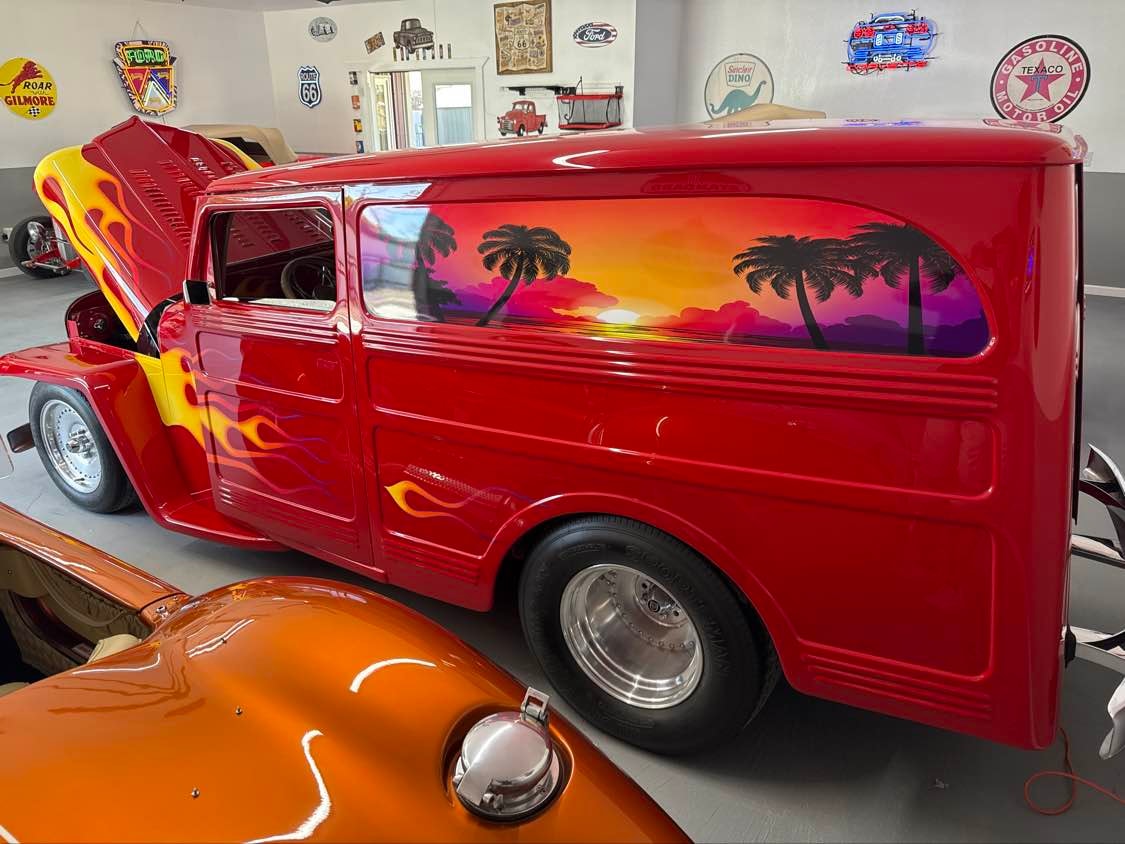 Custom red hot rod panel truck with flame paintwork at sunset
